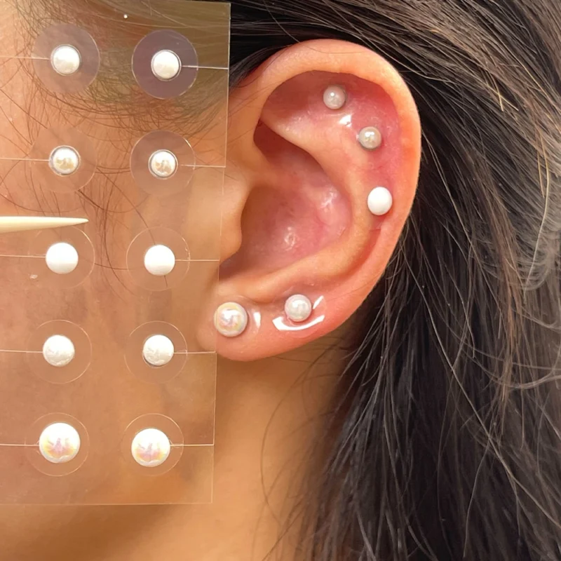 Gold and crystal ear seeds wellness jewelry on ear