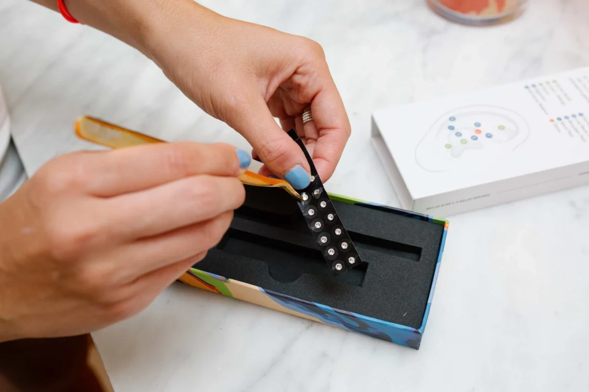 A beautifully organized tray featuring a LINGLONG JUHUO ear seed kit, tweezers, and a mirror in a self-care space.