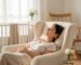 A serene new mother relaxing in a nursery, wearing a gold ear seed for postpartum wellness.